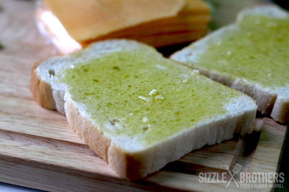 Auf einem Brett liegt mit Knoblauch Öl bestrichenes Sandwichtoast