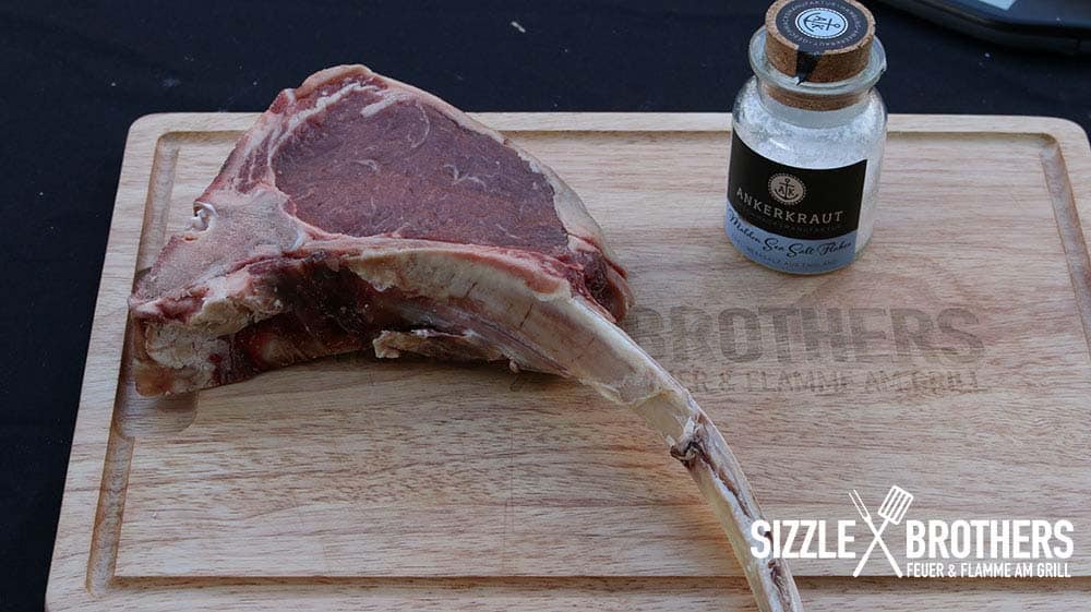 Ein Tomahawk Steak rückwärts grillen. Auf einem Brett liegt das Steak
