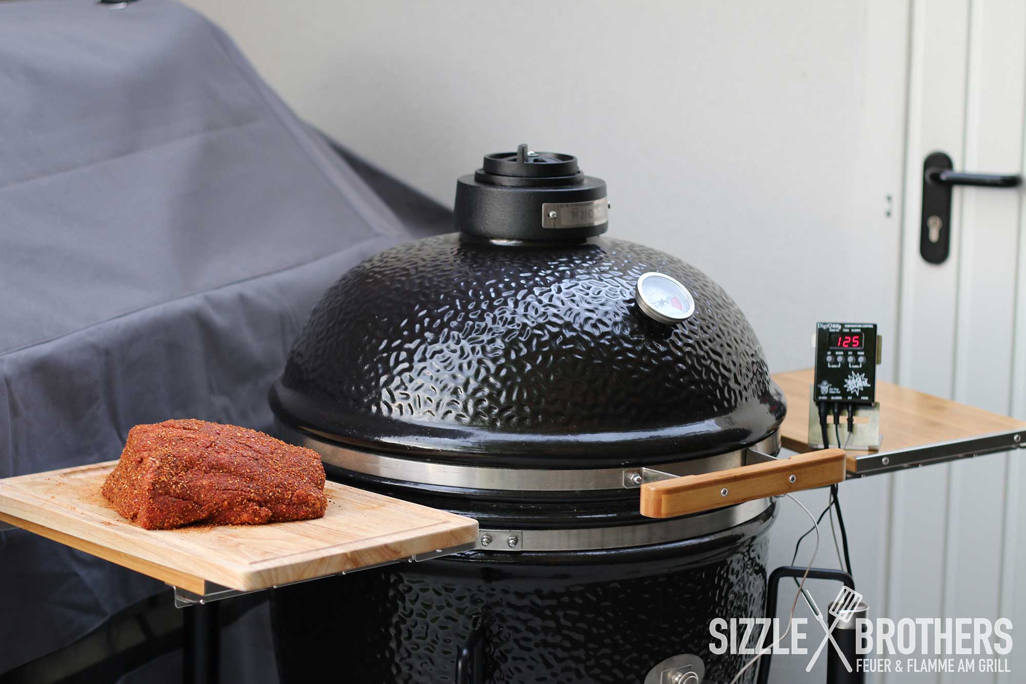 Das gewürzte Rindfleisch neben einem Keramikgrill