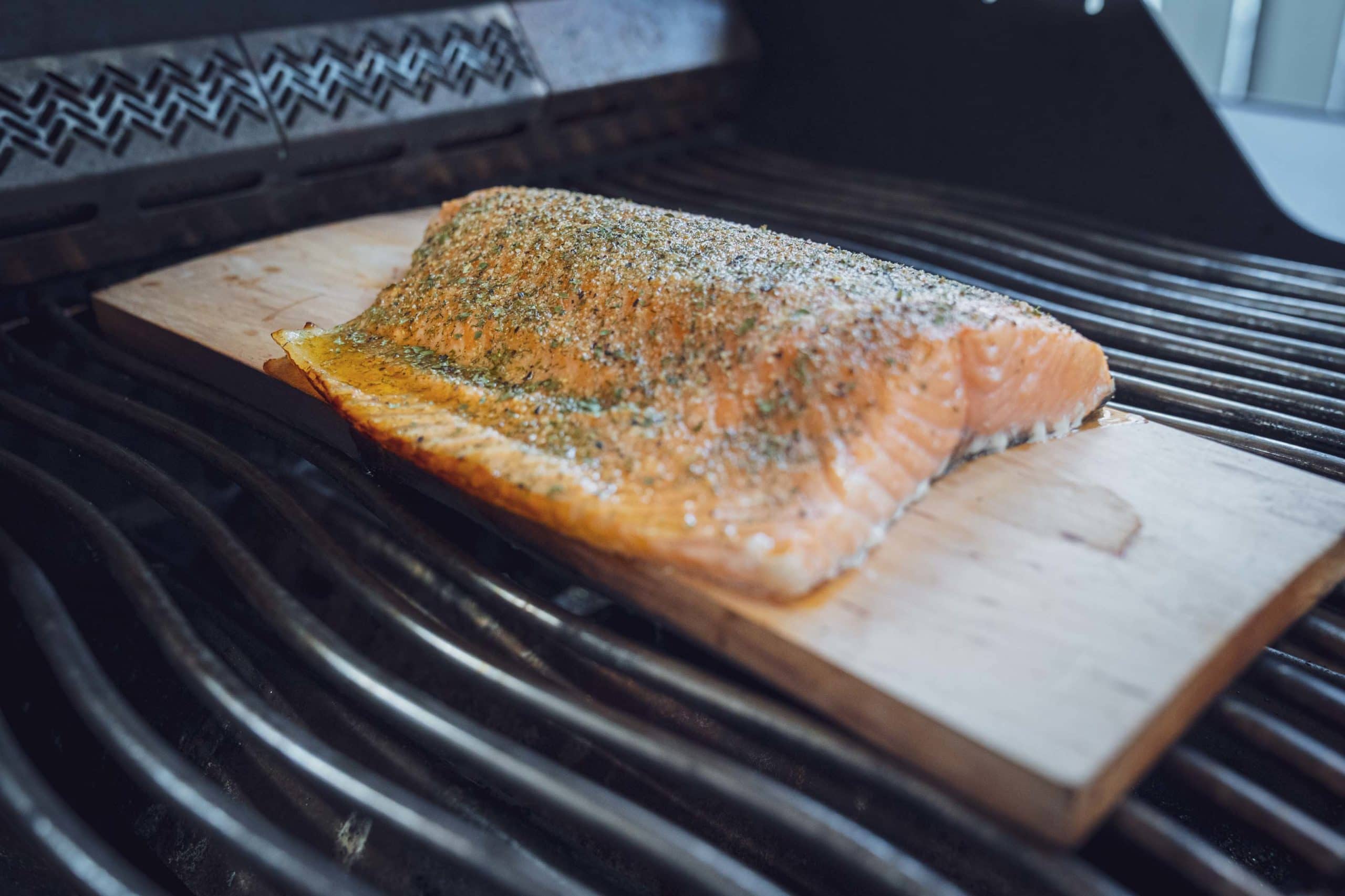 Der Lachs auf einer Holzplanke im indirekten Bereich des Grills