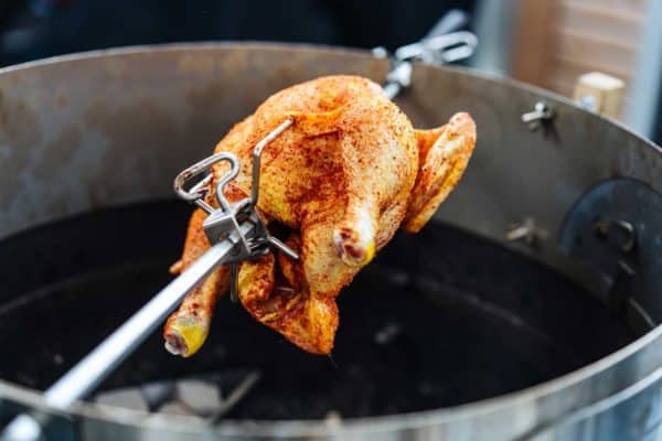 Das Grillhähnchen wurde an einem Drehspieß angebracht und dreht sich über der Glut