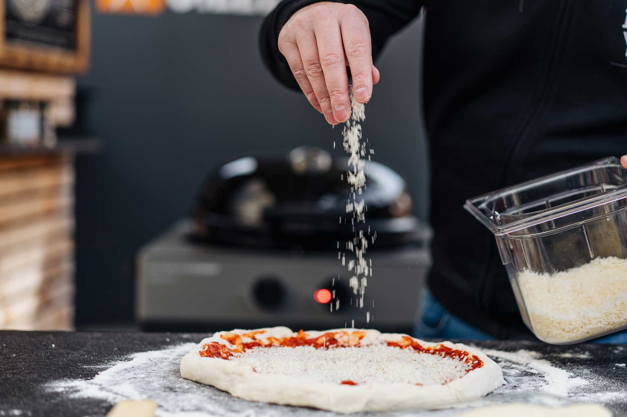 Die New York Pizza wird mit Tomatensauce und Käse belegt