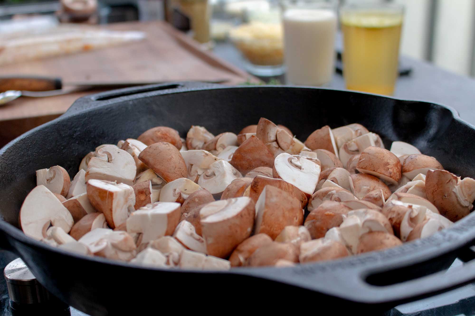 Die geviertelten Champignons werden in einer Gusspfanne angebraten