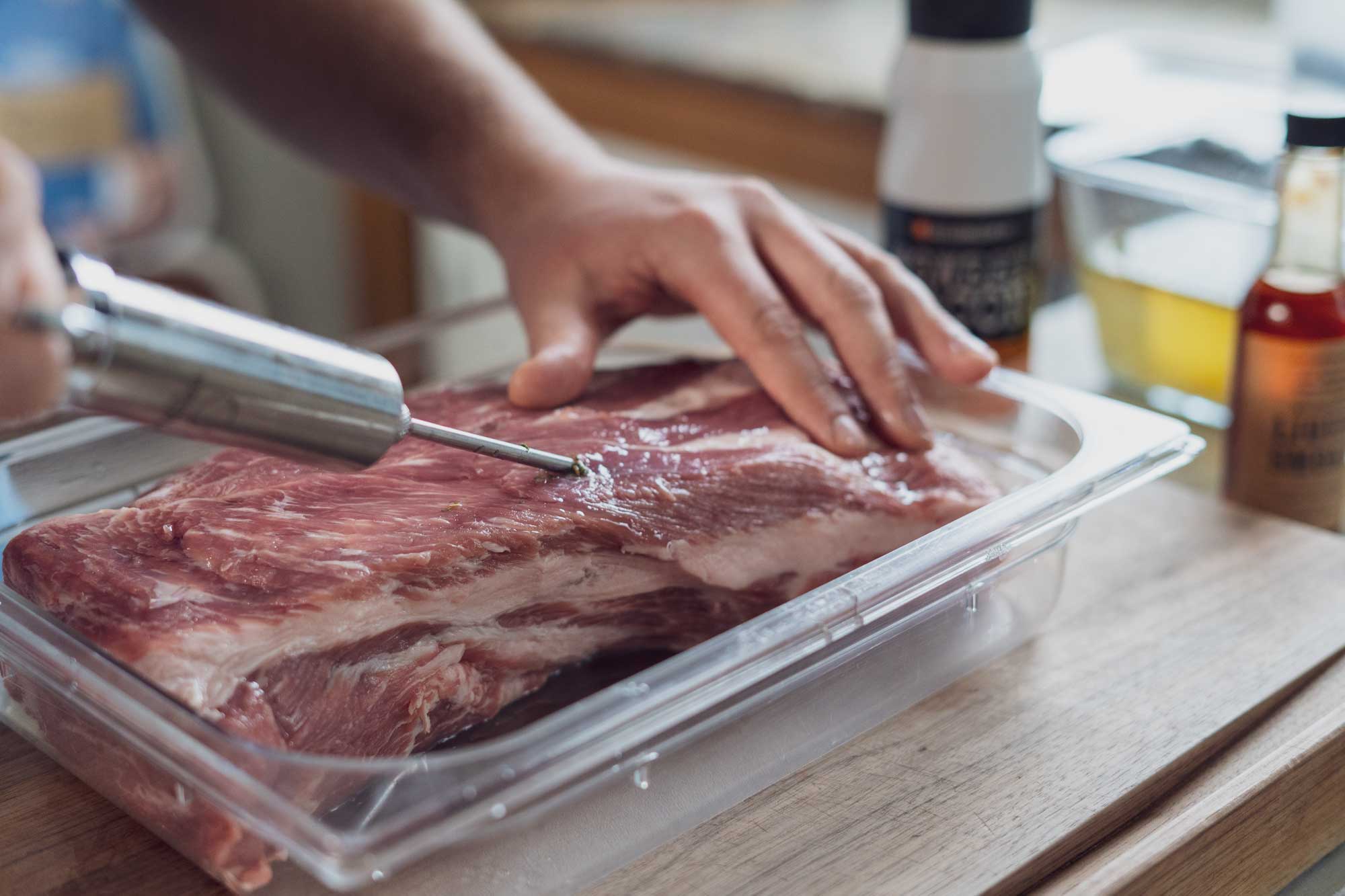 Der Schweinenacken wir mit Hilfe einer Marinierspritze gewürzt