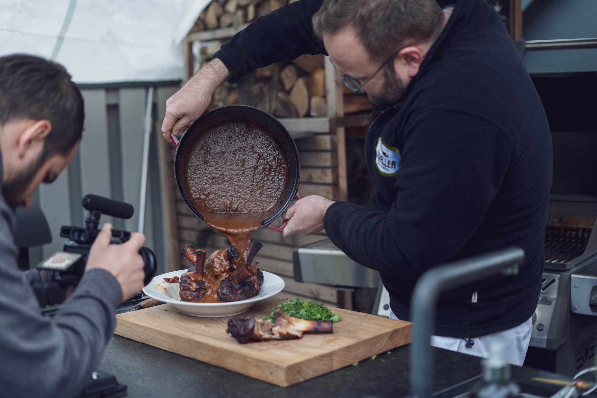 Die Sauce über die Schweinshaxen geben