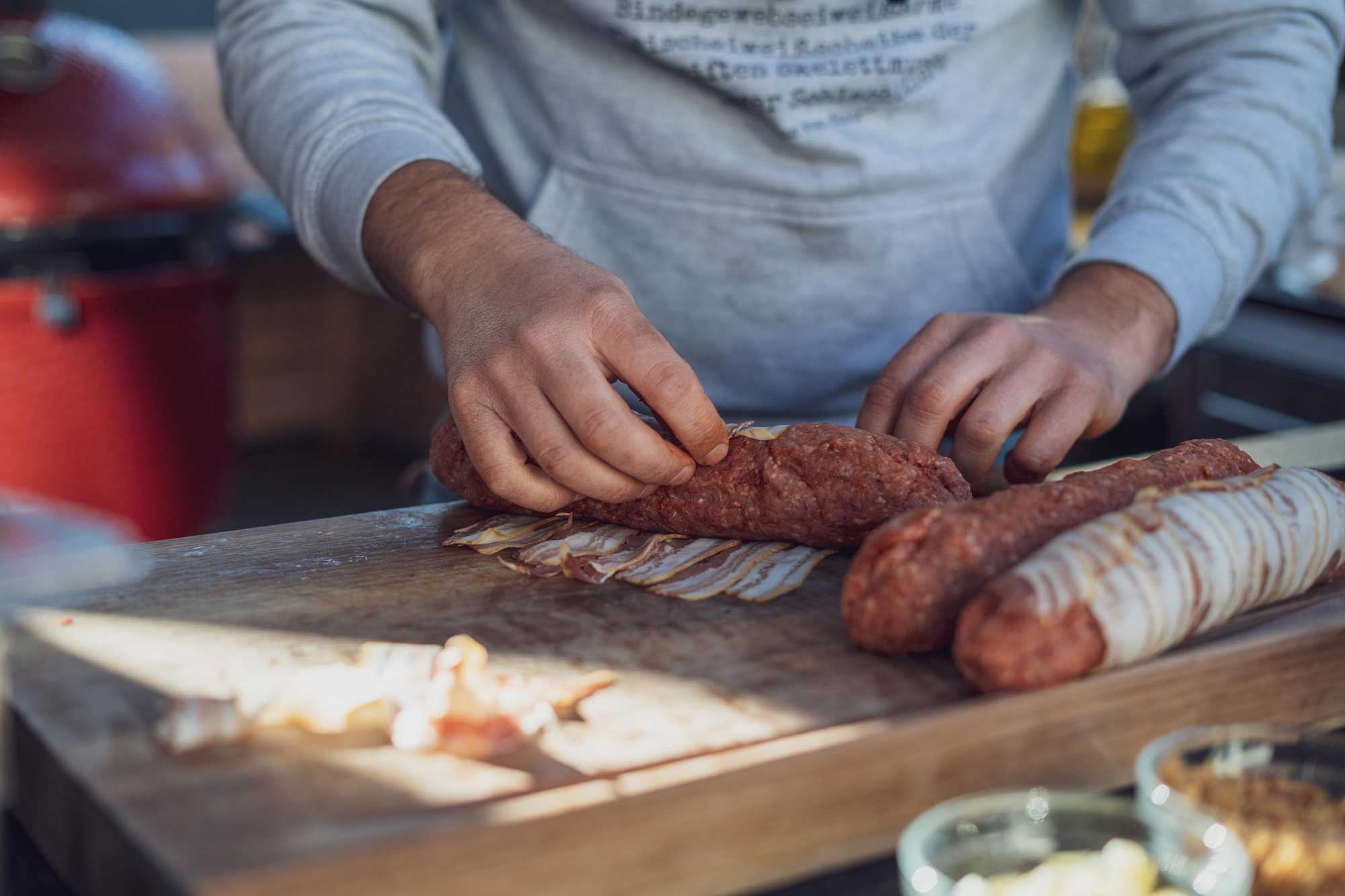Die Wurst wird mit Hack und Käse ummantelt und in Bacon gewickelt