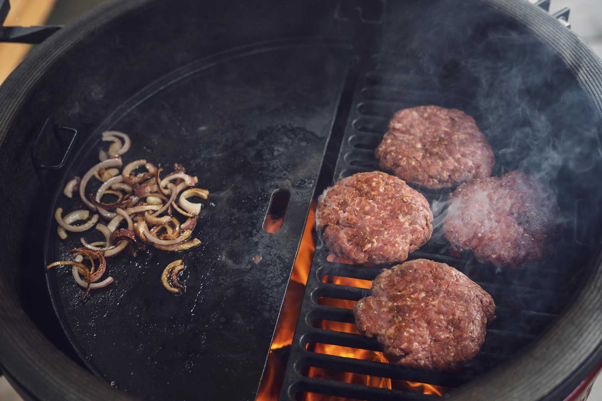 Im Baconfett werden die Zwiebeln gegrillt, während die Patties von dem Flammen geküsst werden