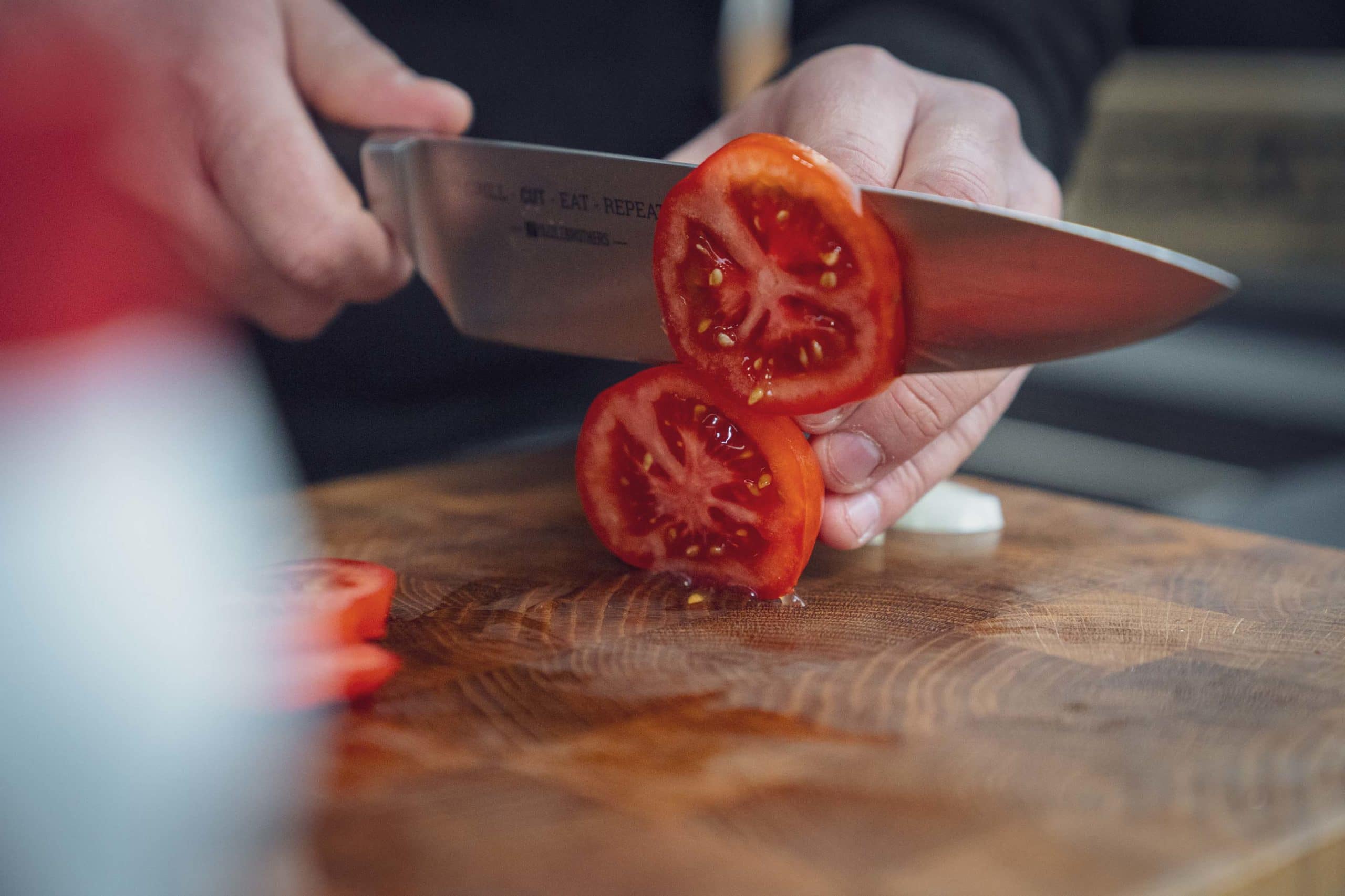 Tomaten werden mit dem Kochmesser klein geschnitten