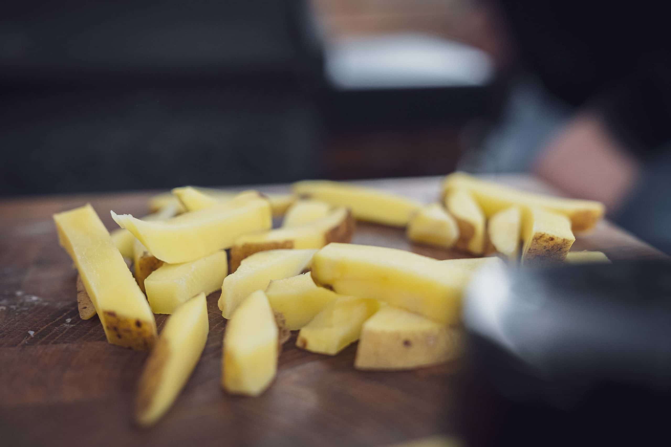 Kartoffeln in gleichgroße Stifte oder Formen für Wedges schneiden