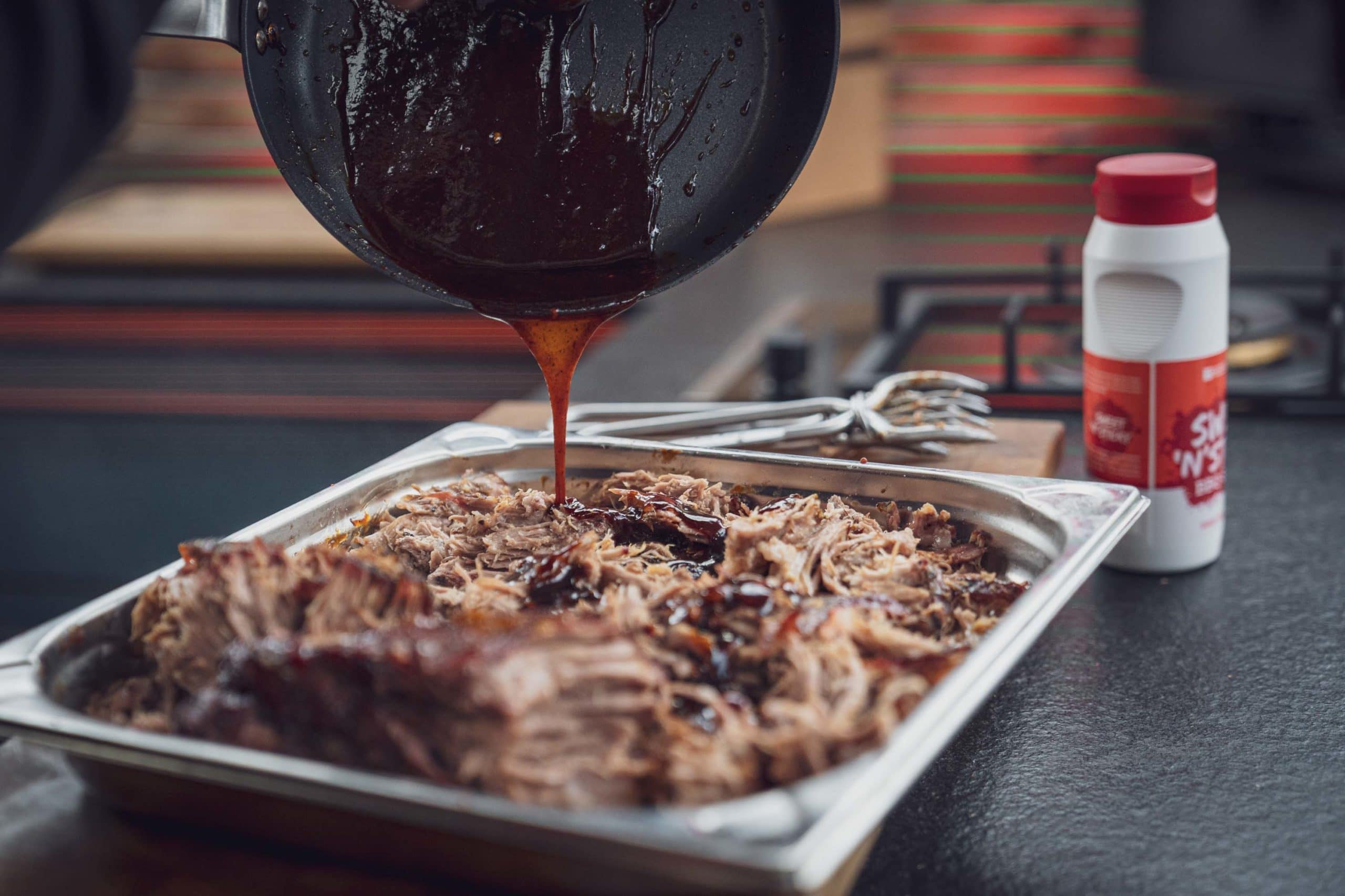 Pulled Pork wird mit Sauce übergossen
