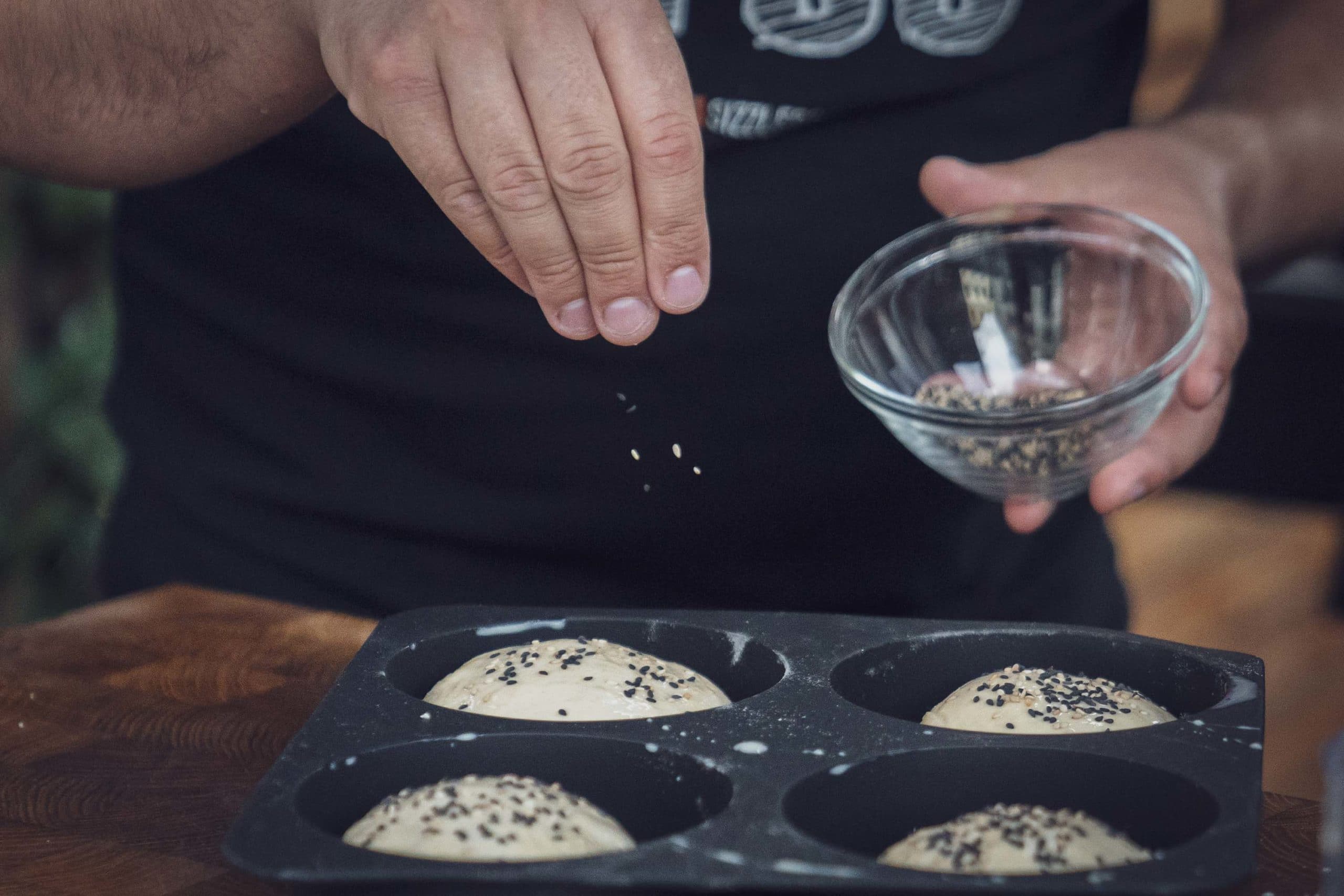Burger Brötchen Teiglinge in Silikonbackform mit Sesam bestreuen