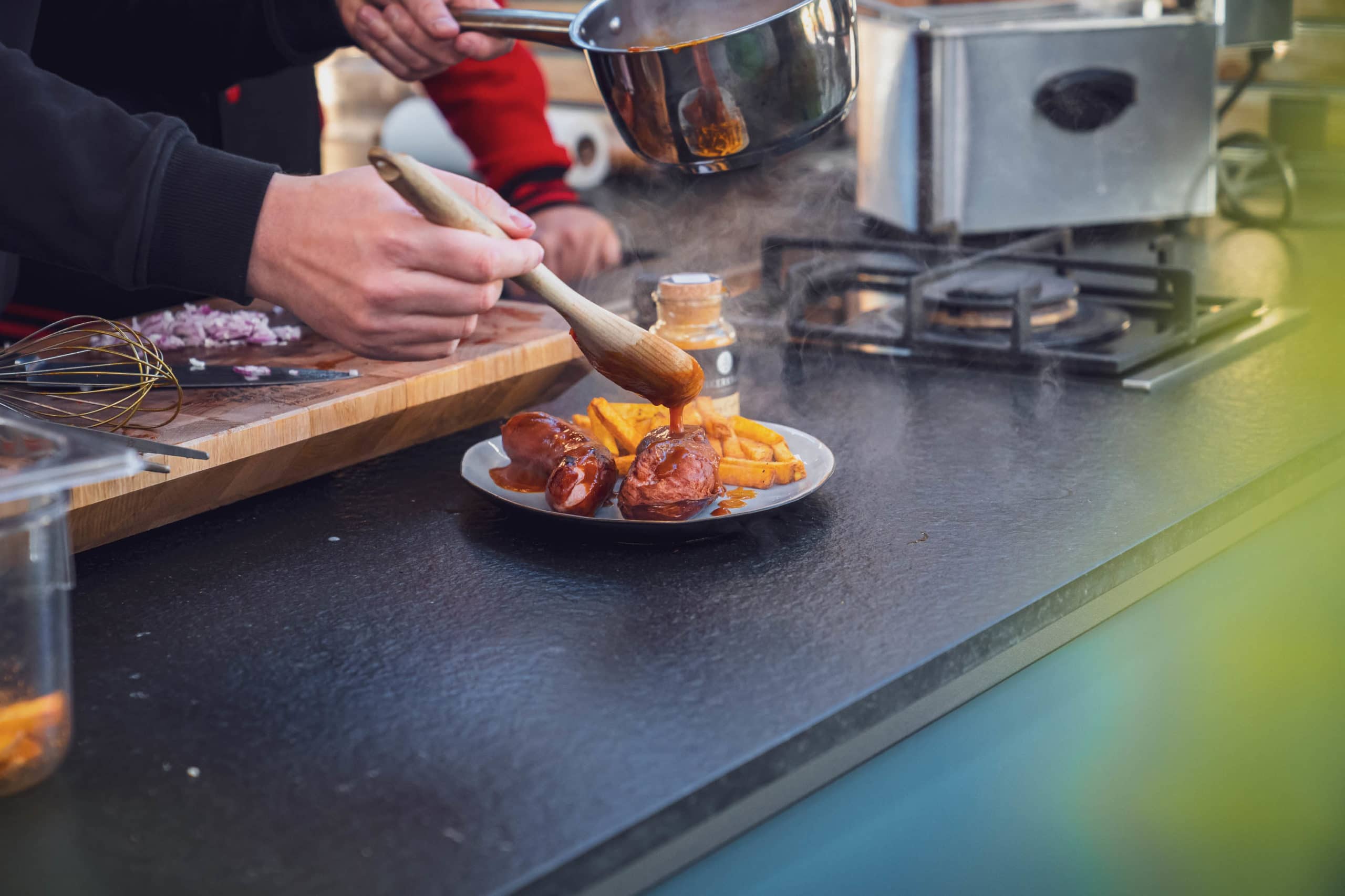 Sauce wird über die Currywurst gegeben