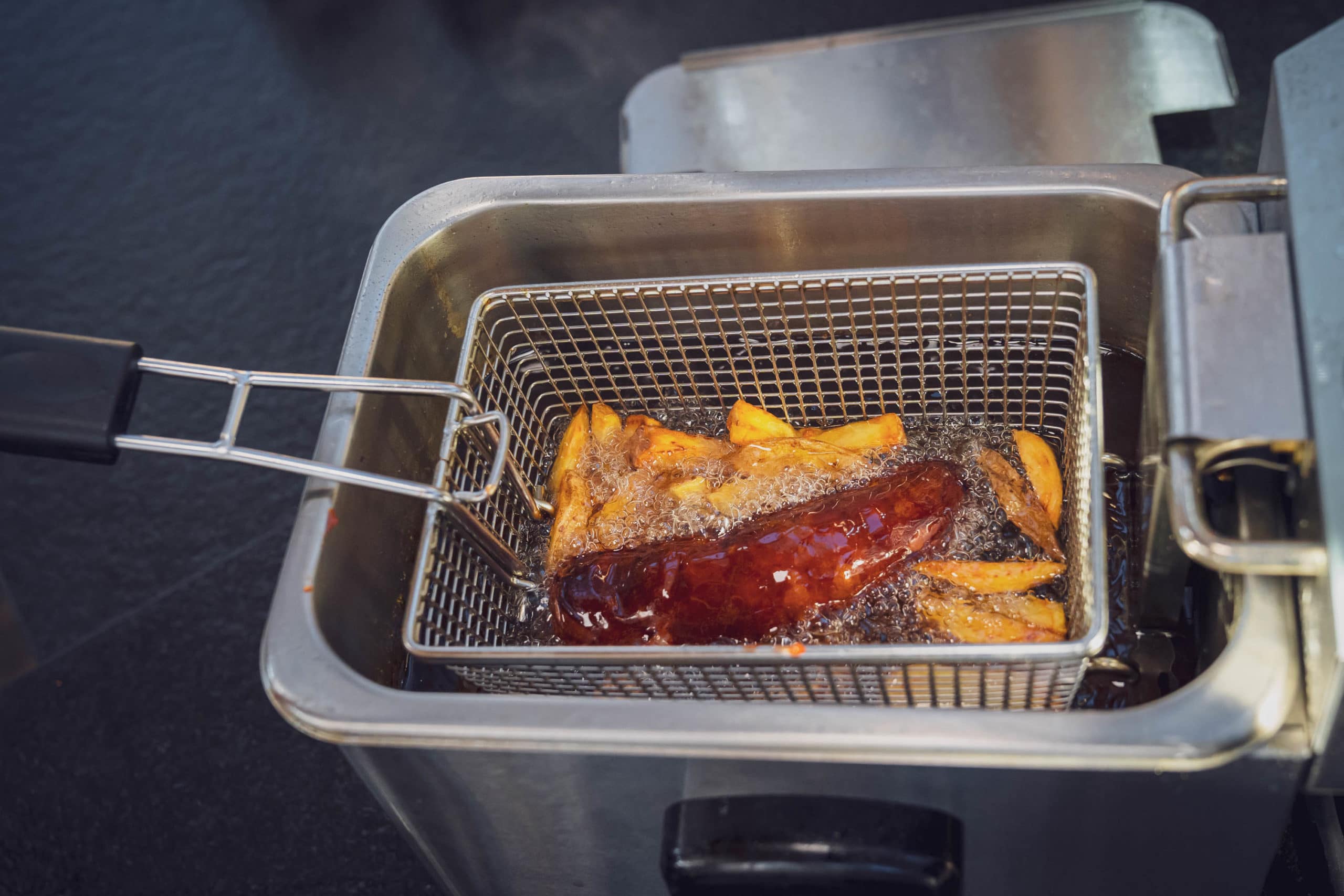 Pommes und Currywurst liegen im Fett