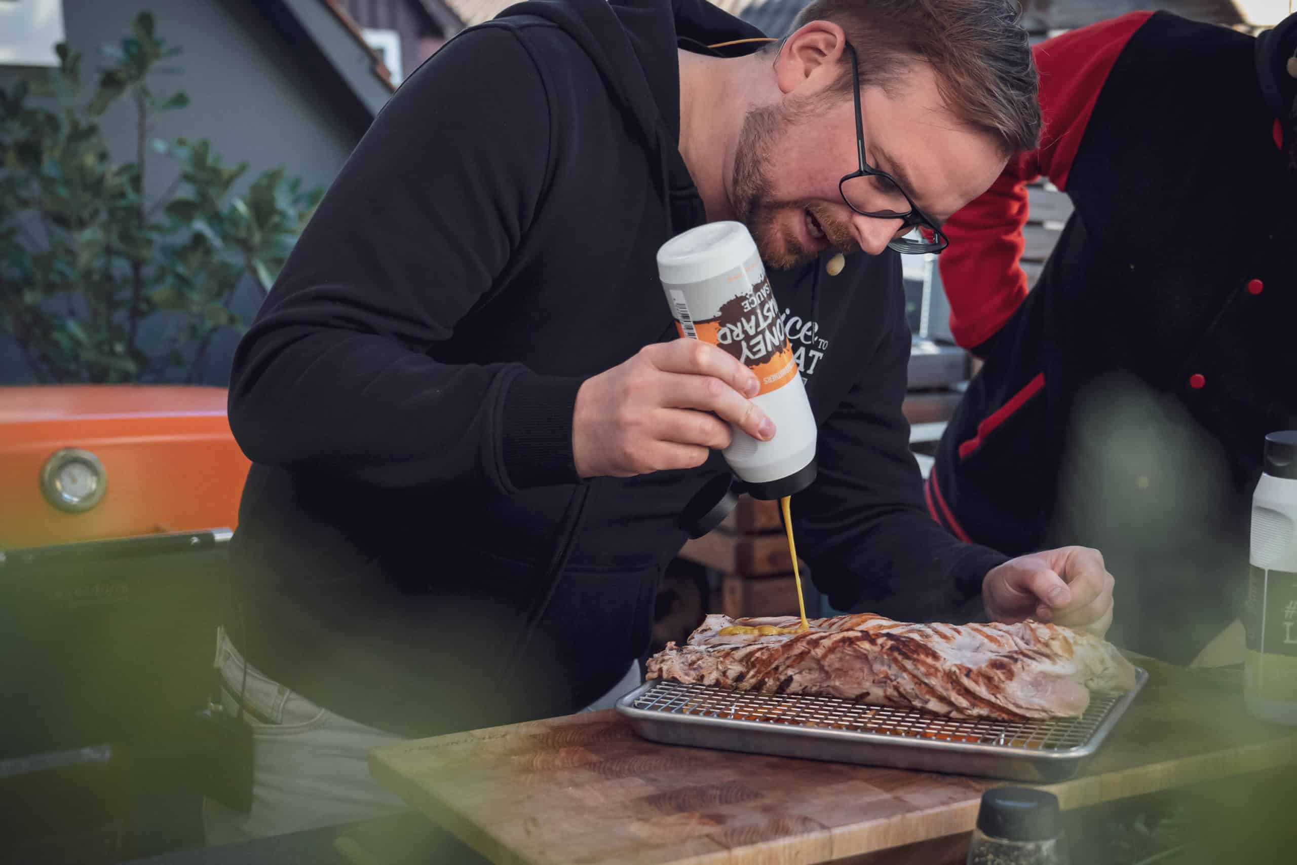 Julian gibt Honig-Senf Sauce über das Fleisch