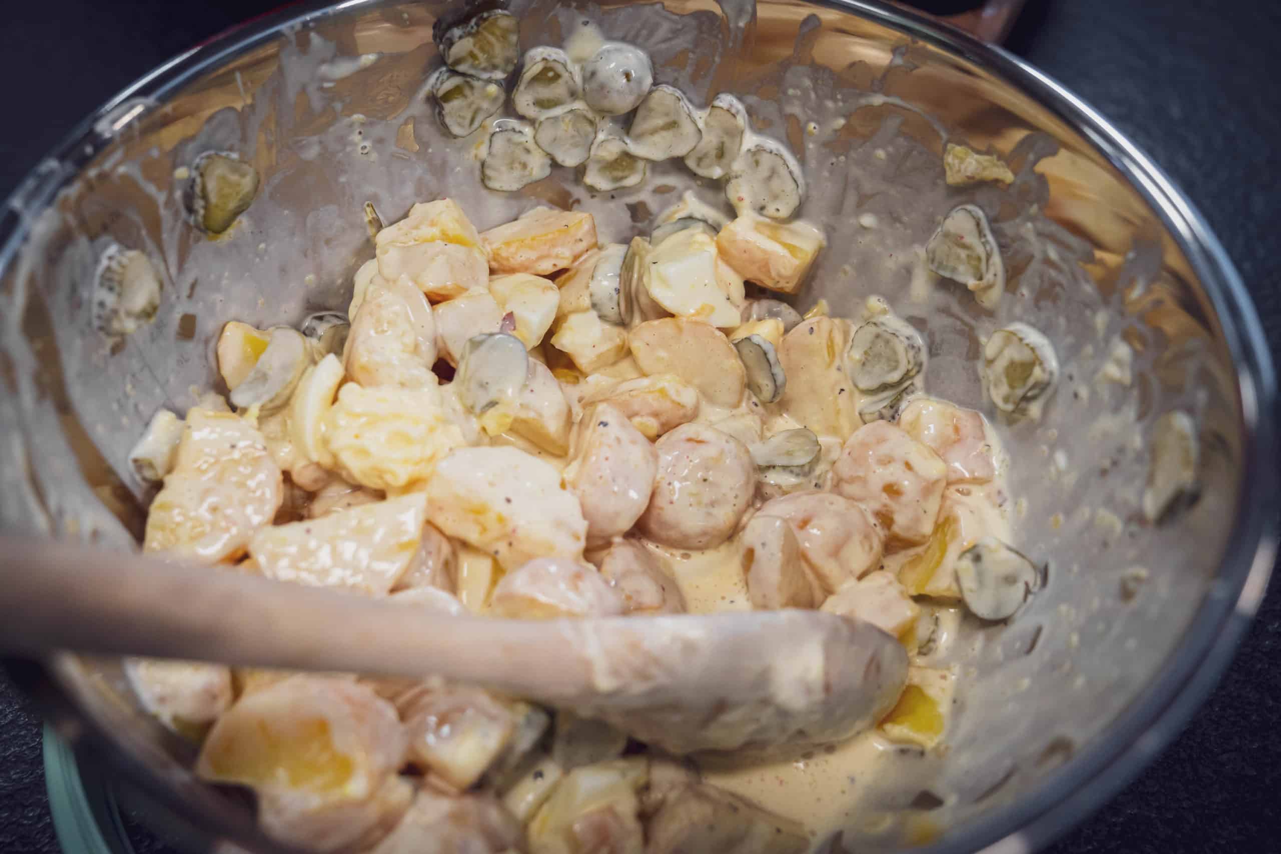 In einer Schüssel wird der Kartoffelsalat fertig angerührt