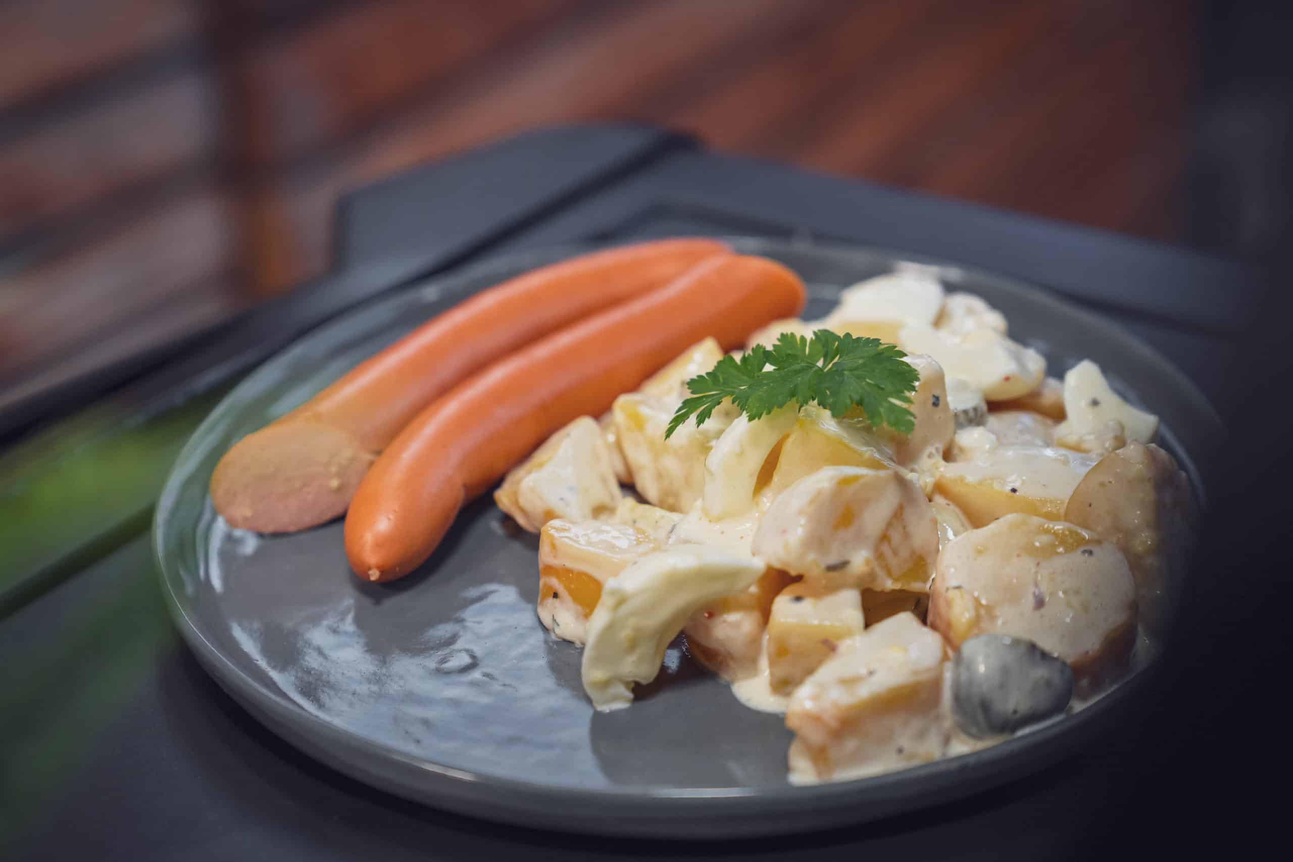 Kartoffelsalat mit Mayonnaise und warmen Bockwürsten auf einem Teller