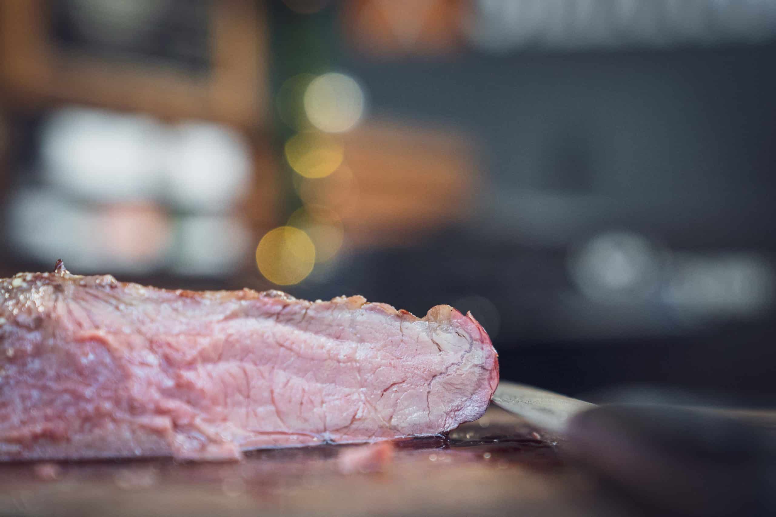 Das Tri Tip vom Smoker liegt angeschnitten auf einem Holzbrett. Die Farbe ist zart rosa