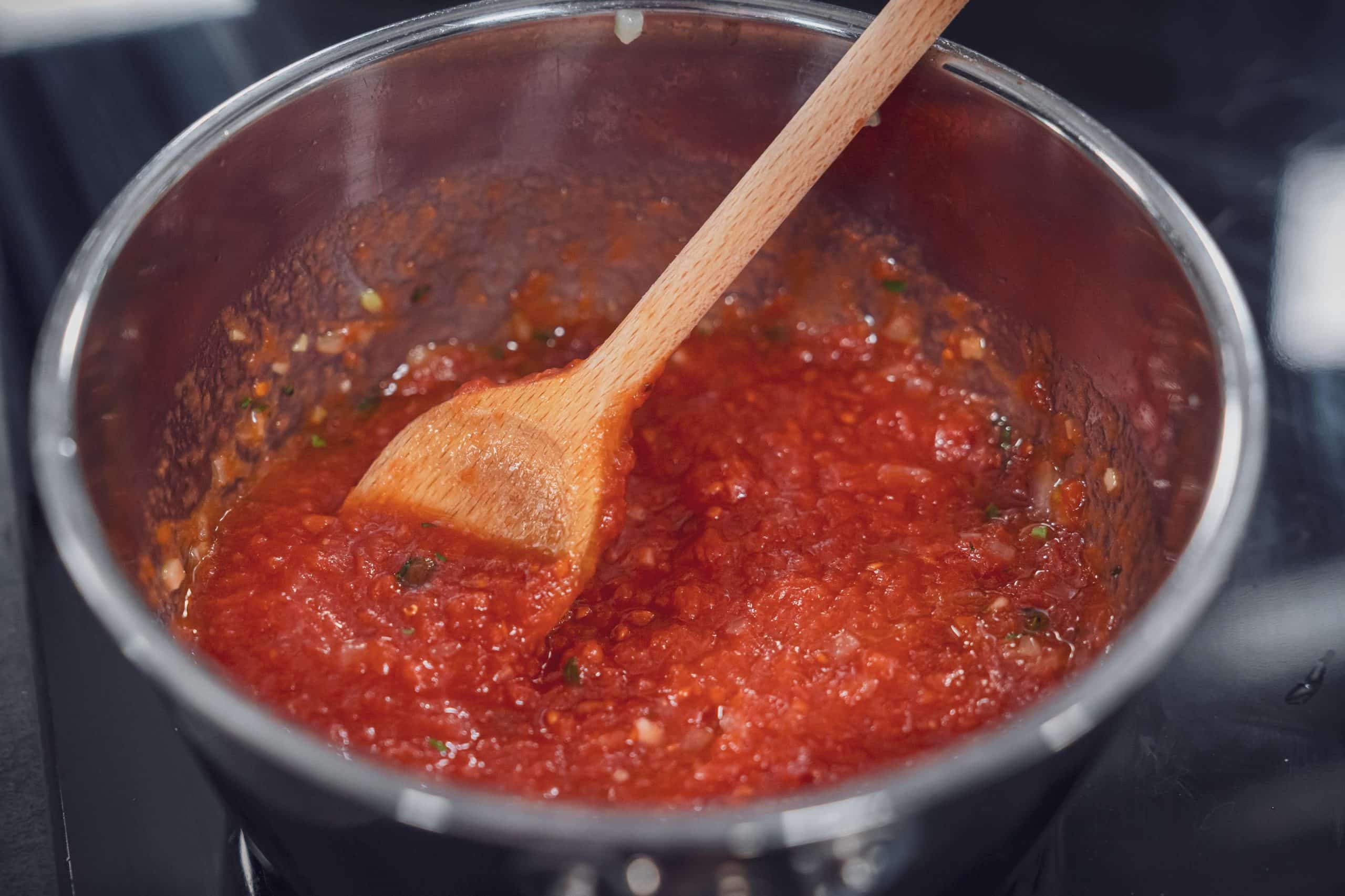 Gehackte Tomaten werden in den Topf gegeben und verrührt
