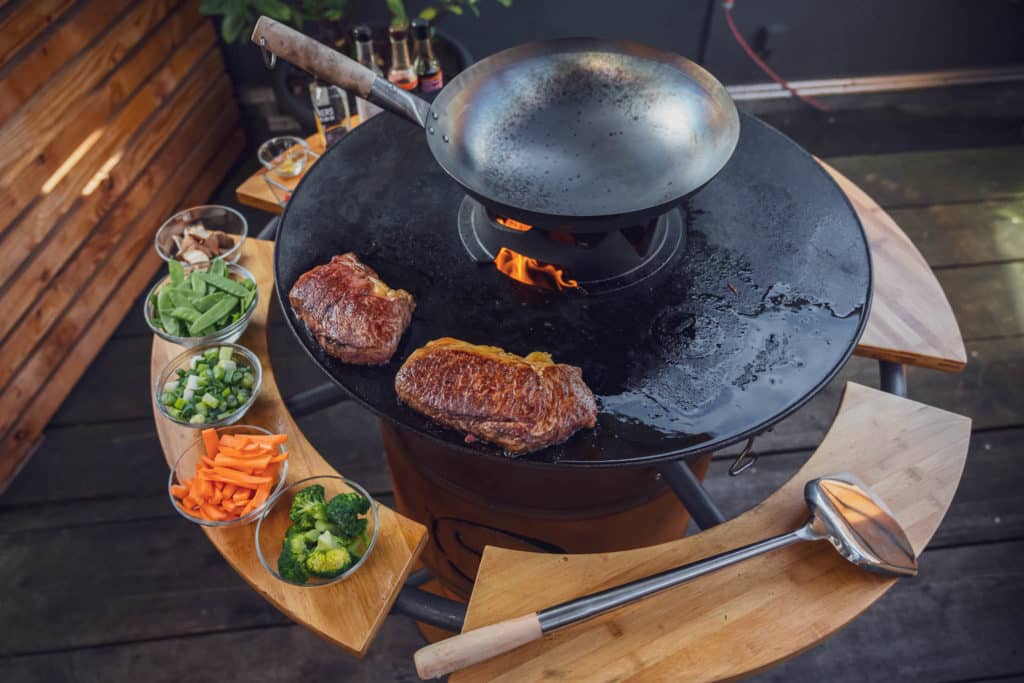 Steaks auf der Plancha und bereitstehendes Gemüse für den Wok