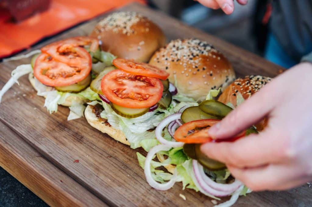 Der Stuffed Cheeseburger wird mit Tomaten, Gurken, Zwiebeln und Salat belegt