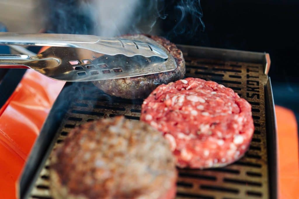 3 Patties liegen auf einem heißen Grill