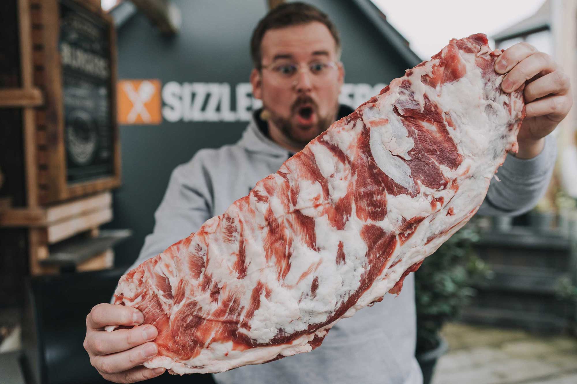 Spareribs grillen: Julian hält XXL Rippchen in die Kamera